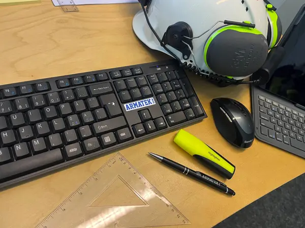 Tastatur, skisser og vernehjelm på kontorpult