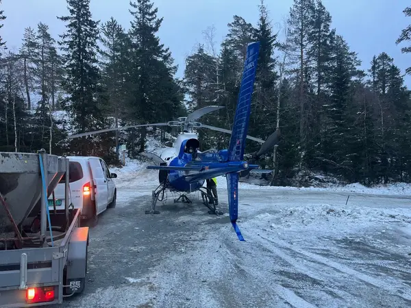 Helikopter parkert ved biler på en snødekt plass