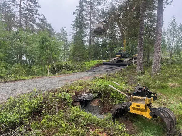 Gravemaskin i arbeid på en skogsvei